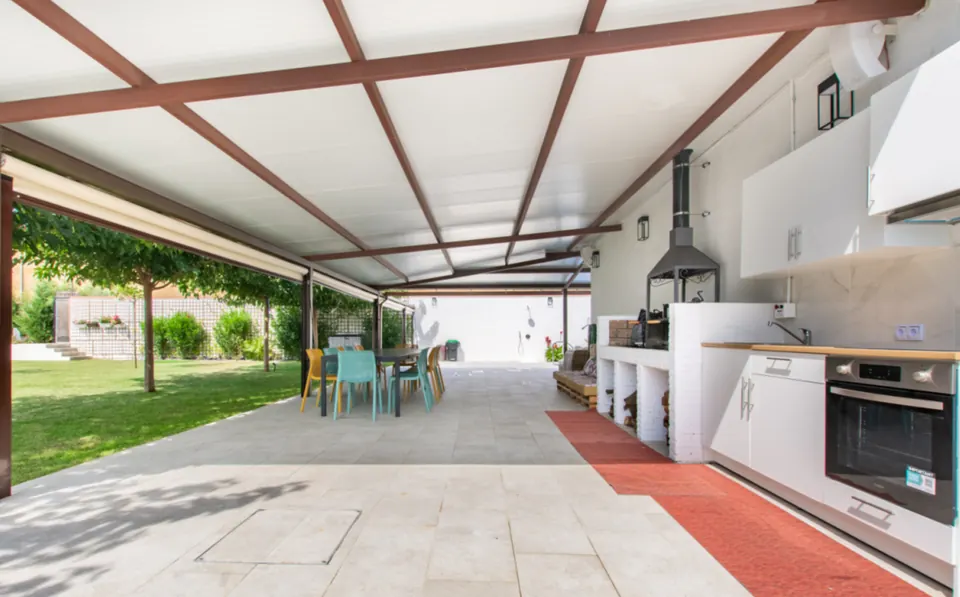 La cocina exterior con barbacoa y horno bajo la pérgola