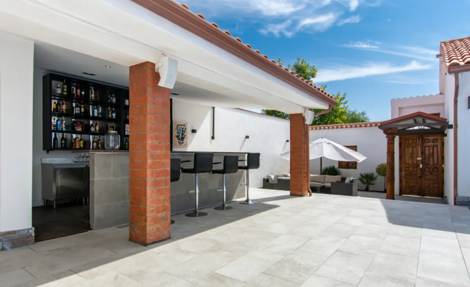 La barra del bar entre pilares de ladrillo, con el lounge al fondo