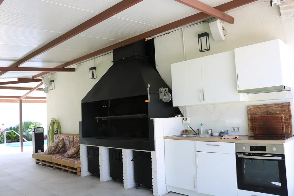 La cocina exterior con fregadero y horno, bajo la pérgola de la barbacoa