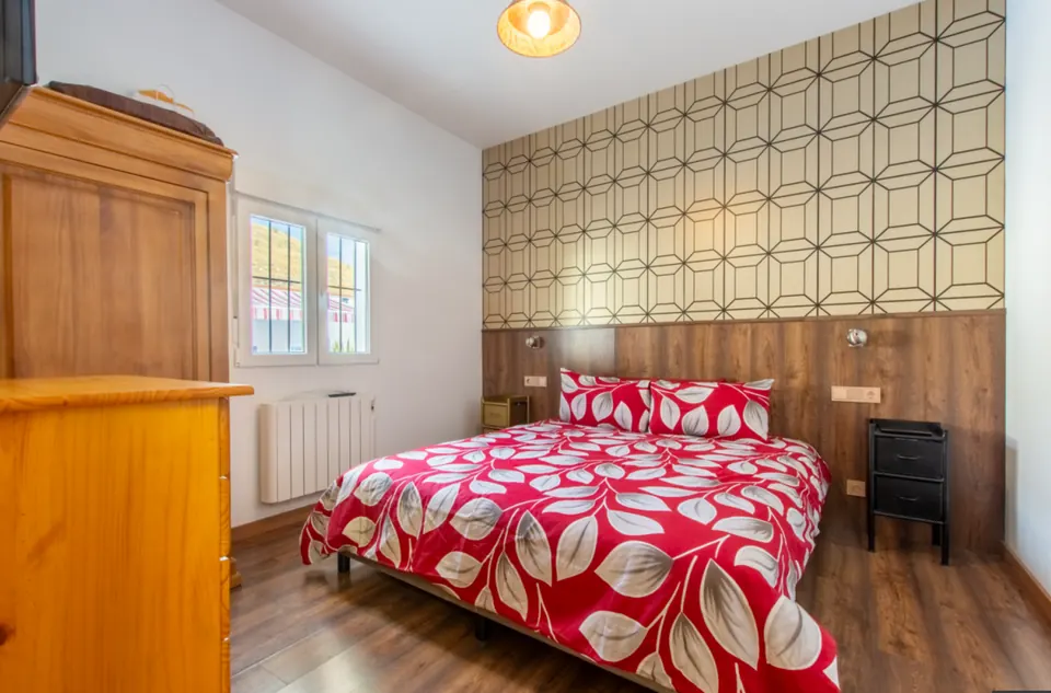 Dormitorio con cabecero de madera y papel geométrico crema