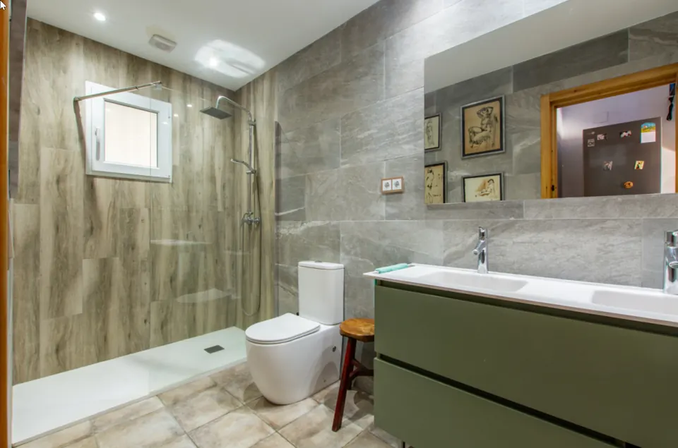 Baño reformado en piedra gris con ducha de obra