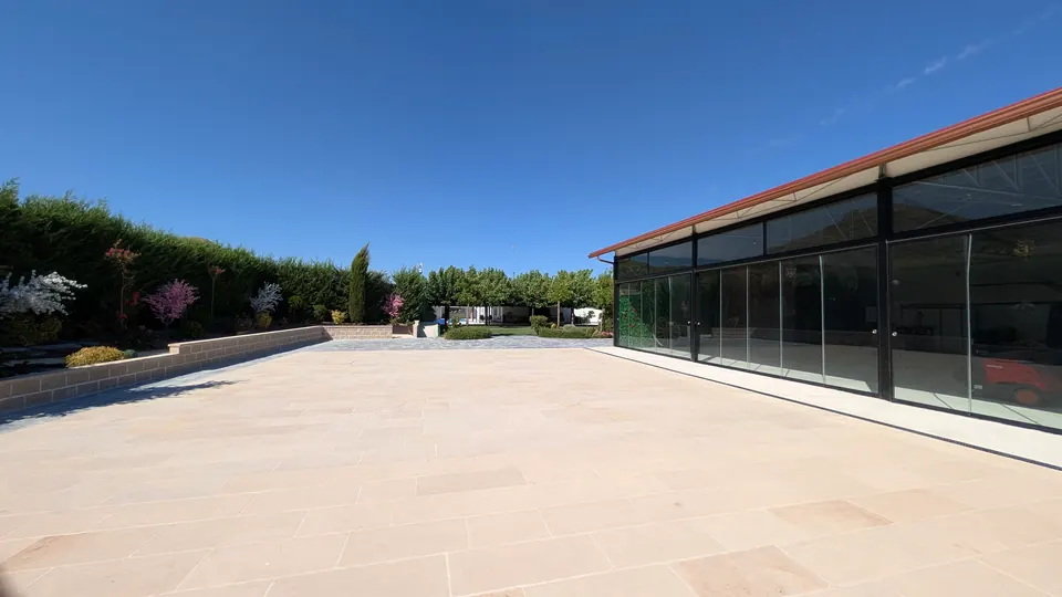 La gran explanada de travertino bajo el cielo azul, con la cristalera del hangar a un lado