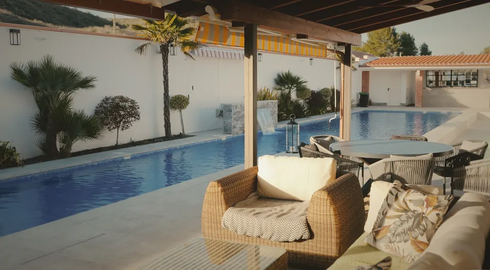 Zona de descanso junto a la piscina, con muebles de ratán